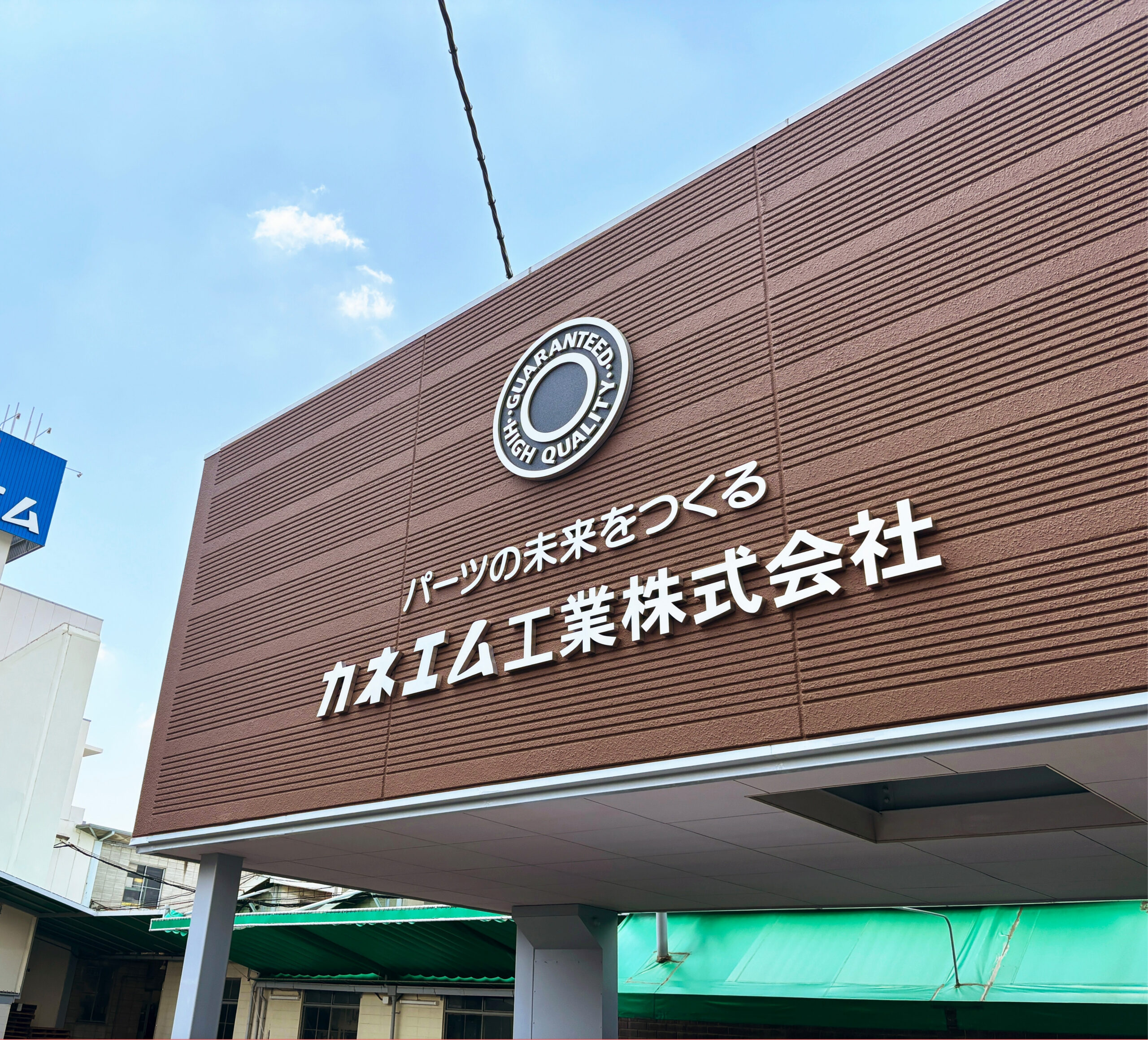 斜め下から見たカネエム工業株式会社様の外壁ファサードサイン完成写真